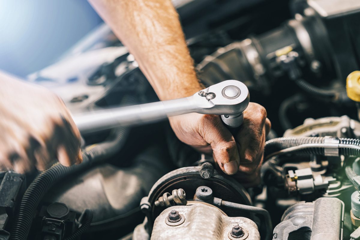 Hands of car mechanic in auto repair service with wrench